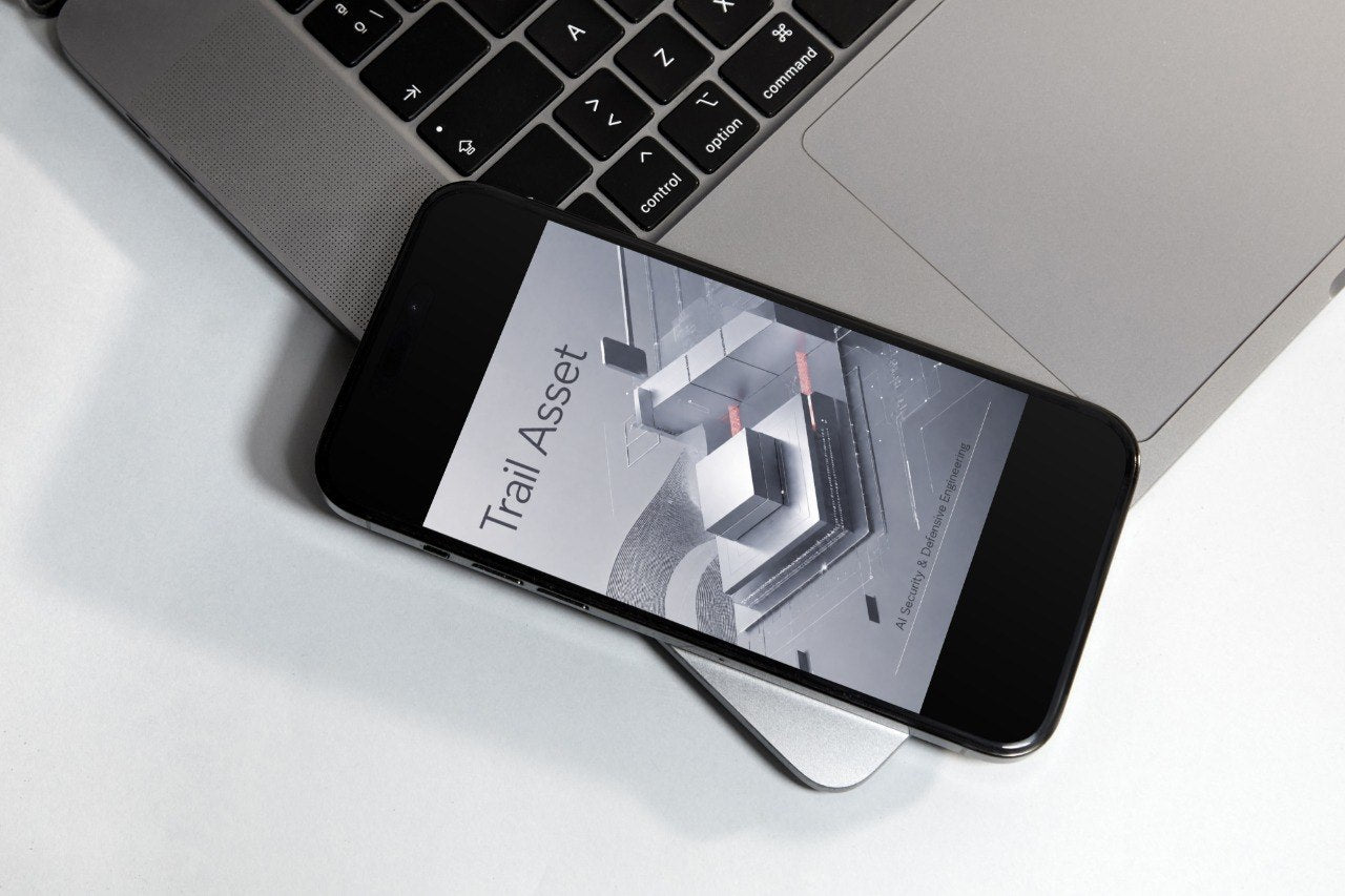 A black smartphone lying diagonally on top of a silver laptop on a white surface, with the phone screen displaying the text 'Drift Blueprint'.